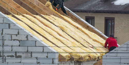 Foto Roofer builder worker installing roof insulation material on new house under con