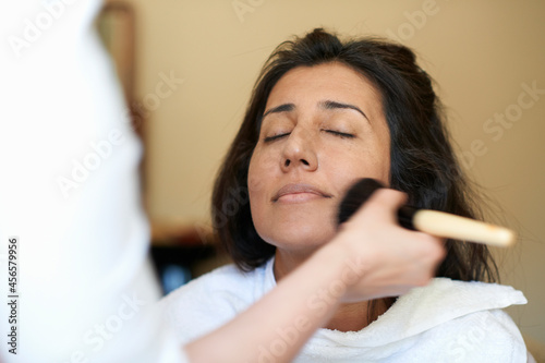 Fotografi Hands of female make up artist applying blusher to clients cheek
