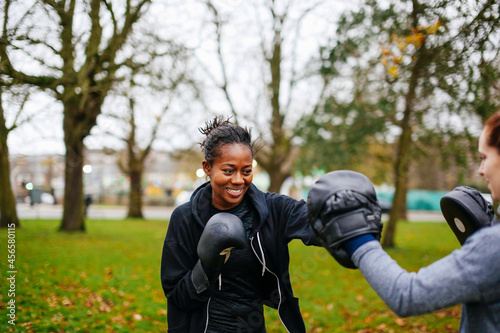 Young adult female boxers training together in park