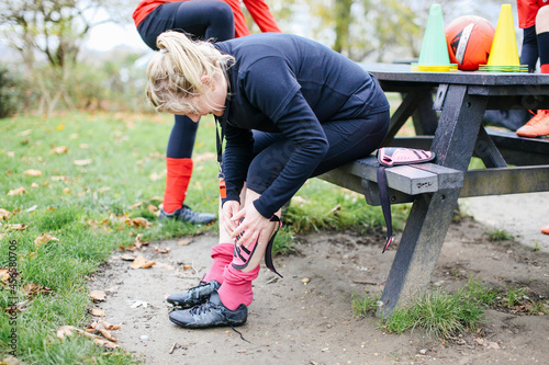 Fotografie Female soccer player putting on shin pad