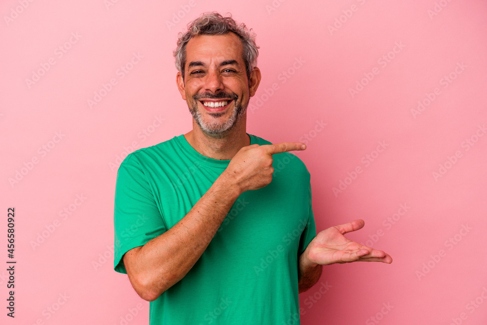 Middle age caucasian man isolated on pink background excited holding a copy space on palm. Middle age caucasian man isolated on pink background excited holding a copy space on palm.