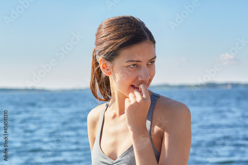 Women in front of ocean with finger in mouth looking away