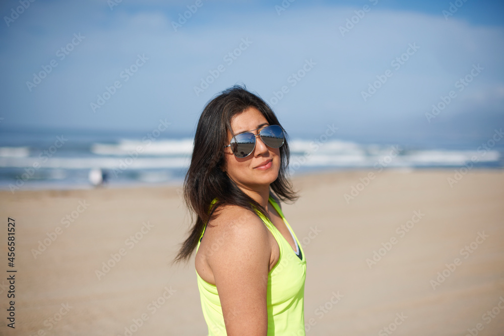 Woman wearing sunglasses on beach looking at camera