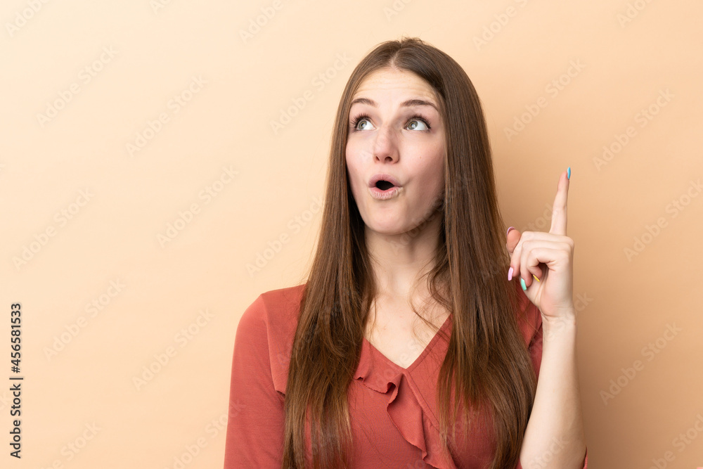 Young caucasian woman isolated on beige background thinking an idea pointing the finger up Young caucasian woman isolated on beige background thinking an idea pointing the finger up