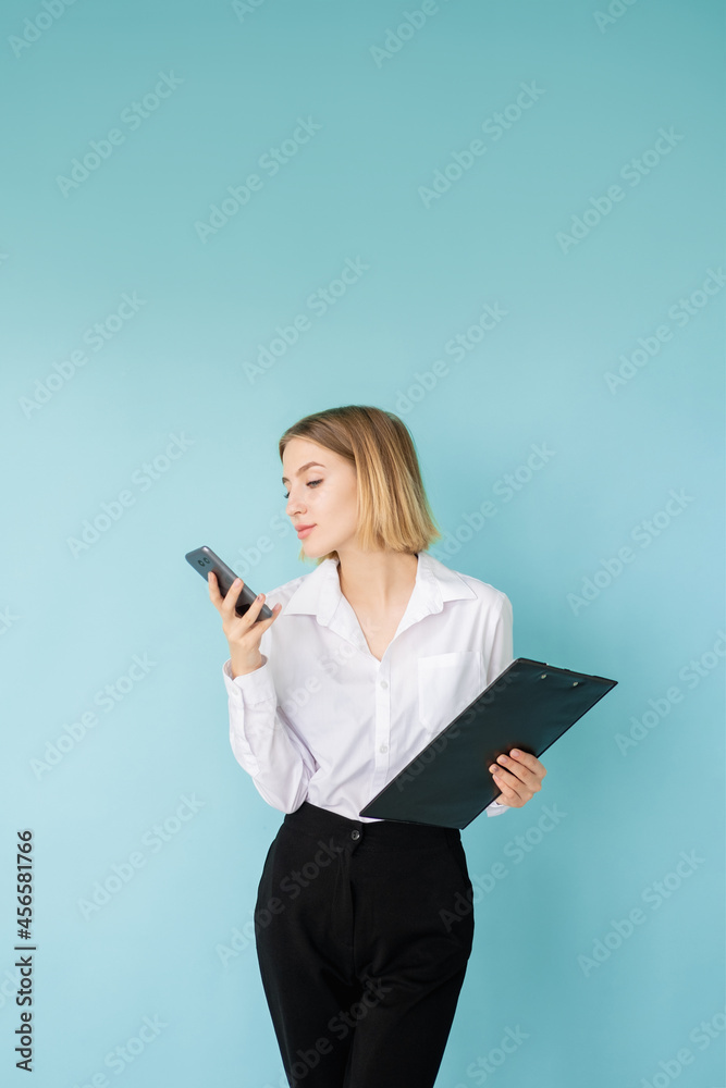 Voice message. Business woman. Time management. Successful planning. Elegant office lady with smartphone and clipboard isolated blue. Voice message. Business woman. Time management. Successful planning. Elegant office lady with smartphone and clipboard isolated blue.