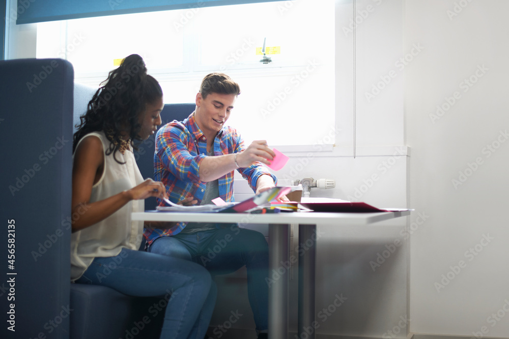 Young female and male college students planning with adhesive notes Young female and male college students planning with adhesive notes