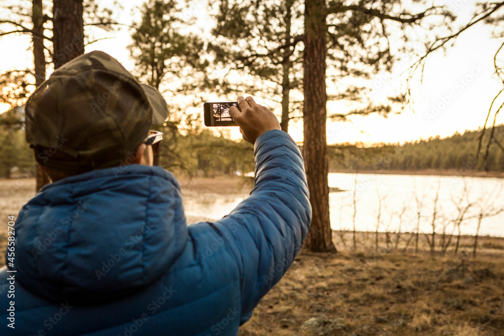 Man taking photograph of lake with smartphone Man taking photograph of lake with smartphone