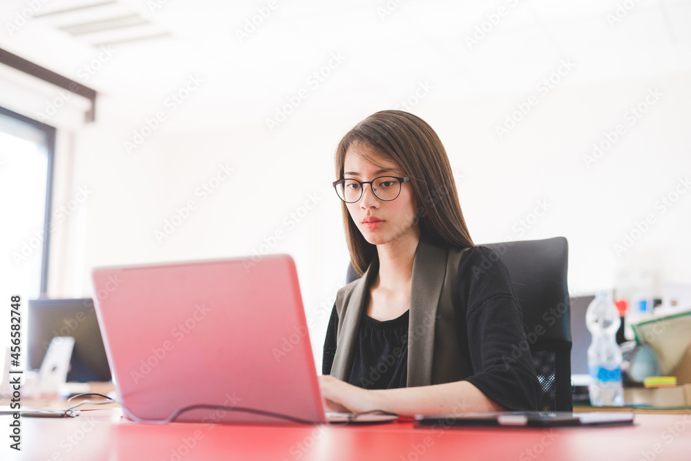 Young woman at office desk typing on laptop Young woman at office desk typing on laptop