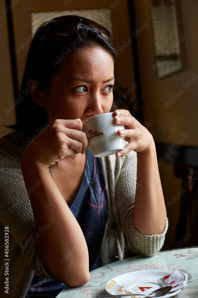 Young woman sitting inside cafe, drinking coffee Young woman sitting inside cafe, drinking coffee