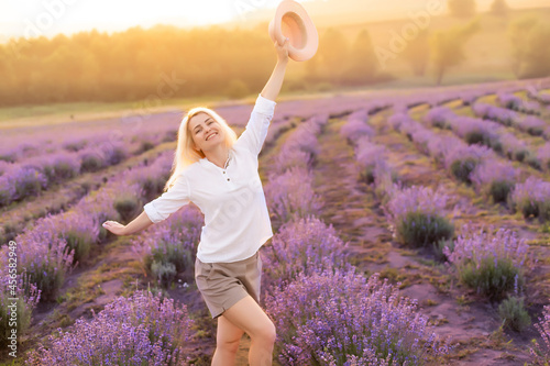 Fototapeta Naklejka Na Ścianę i Meble -  Young woman standing on a lavender field with sunrise on the background