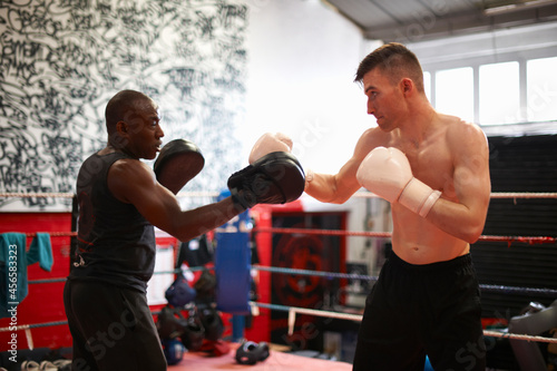 Boxer working out with coach in boxing ring