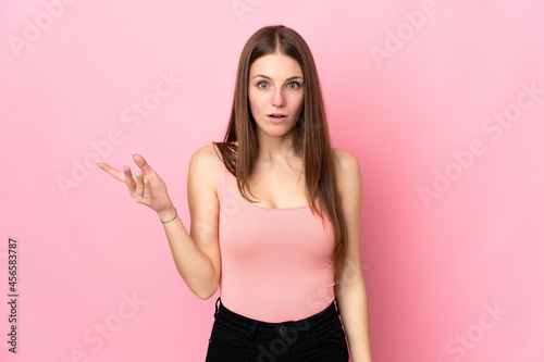 Young caucasian woman isolated on pink background making doubts gesture © luismolinero
