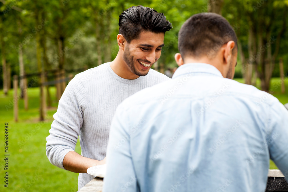 Man having barbecue in park with friend Man having barbecue in park with friend