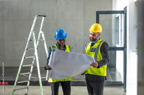 Colleagues with hard hat and hi viz jacket looking at blueprint