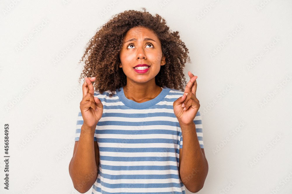 Young african american woman with curly hair isolated on white background crossing fingers for having luck