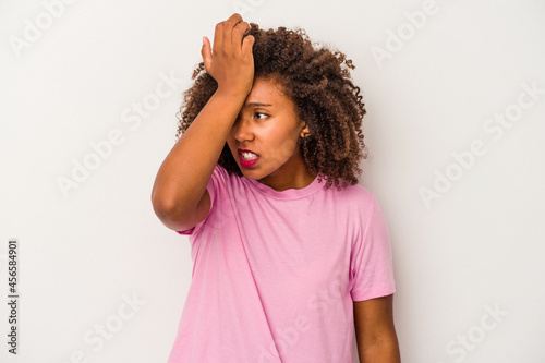 Young african american woman with curly hair isolated on white background forgetting something, slapping forehead with palm and closing eyes. © Asier