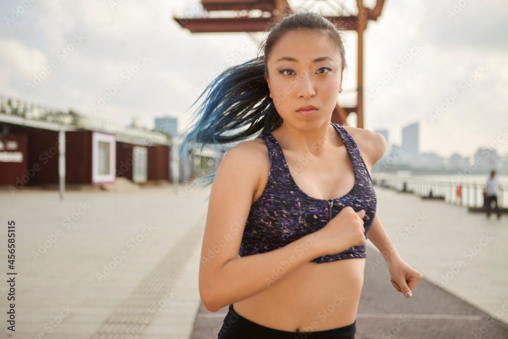 Fototapeta premium Woman jogging looking at camera, South Bund, Shanghai, China