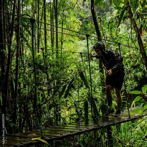 Man crossing rope bridge in forest, Ban Nongluang, Champassak province, Paksong, Laos
