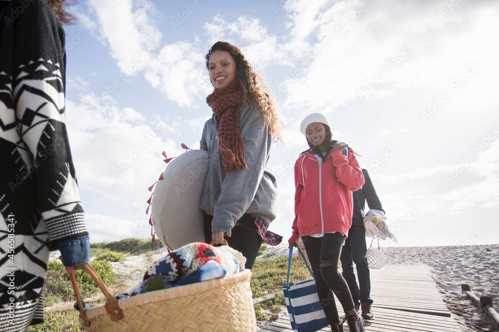 Fototapeta premium Young adult picnicking friends strolling along beach boardwalk, Western Cape, South Africa