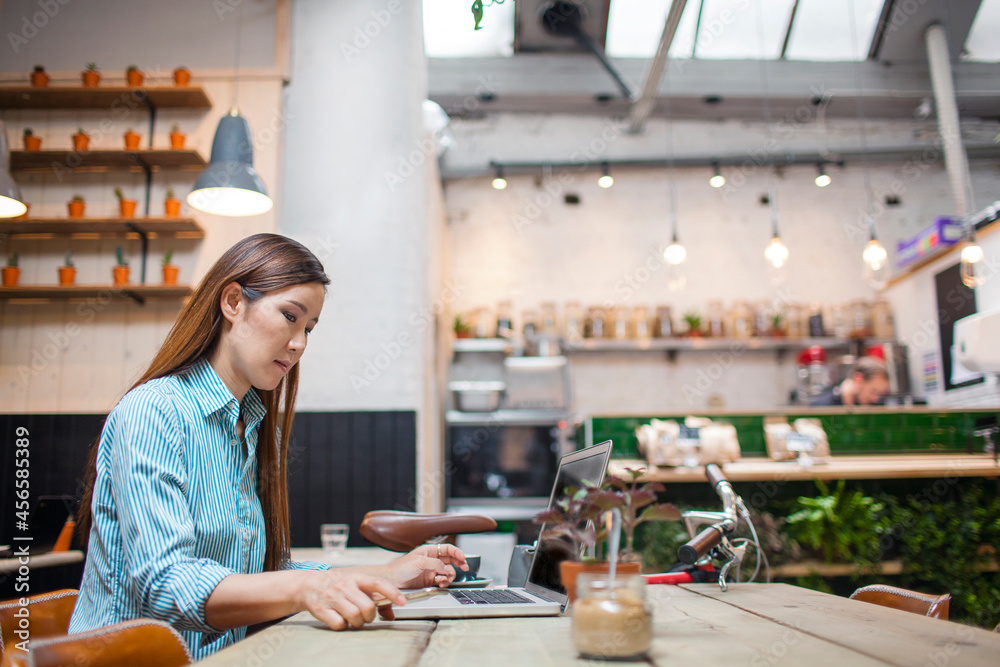 Fototapeta premium Female customer typing on laptop in cafe