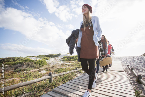 Young adult picnicking friends strolling along beach boardwalk, Western Cape, South Africa