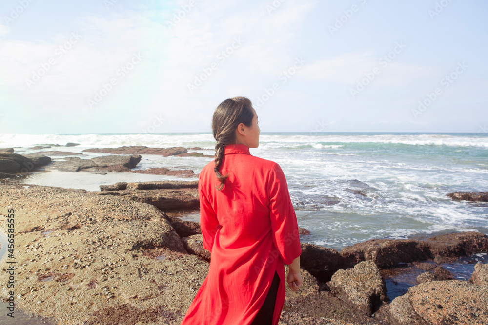 Woman wearing red dress, standing on rocks, looking at sea view, South Africa Woman wearing red dress, standing on rocks, looking at sea view, South Africa