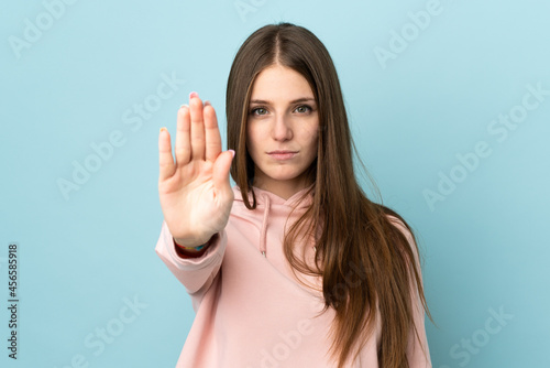 Young caucasian woman isolated on blue background making stop gesture