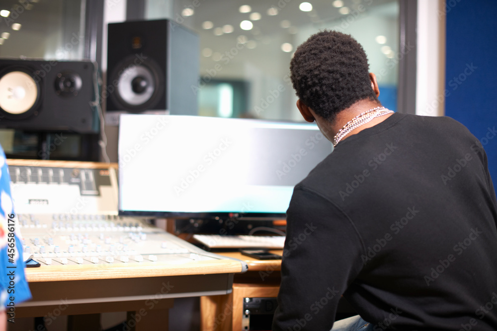 Fototapeta premium Rear view of young male college student at sound mixer in recording studio