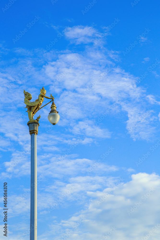 Golden Kinnaree on light pole sky cloud. Lamp sculpture half-bird half-woman. Golden Kinnaree on light pole sky cloud. Lamp sculpture half-bird half-woman.