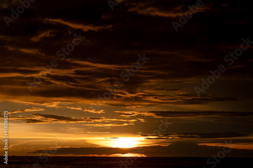 Dark cloudy golden sunset sky on the sea