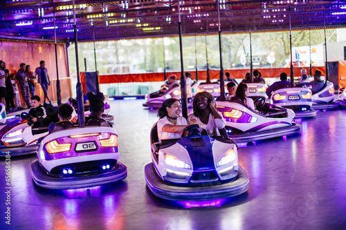Group of friends at funfair, driving bumper cars photo