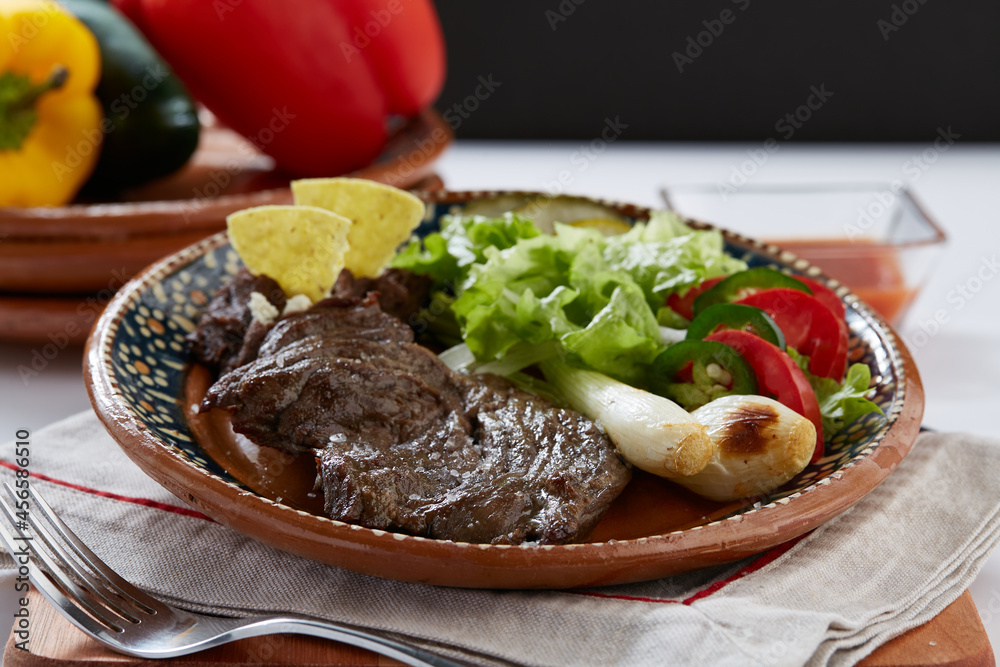 Arrachera servida con frijoles negros refritos, totopos y ensalada Arrachera servida con frijoles negros refritos, totopos y ensalada