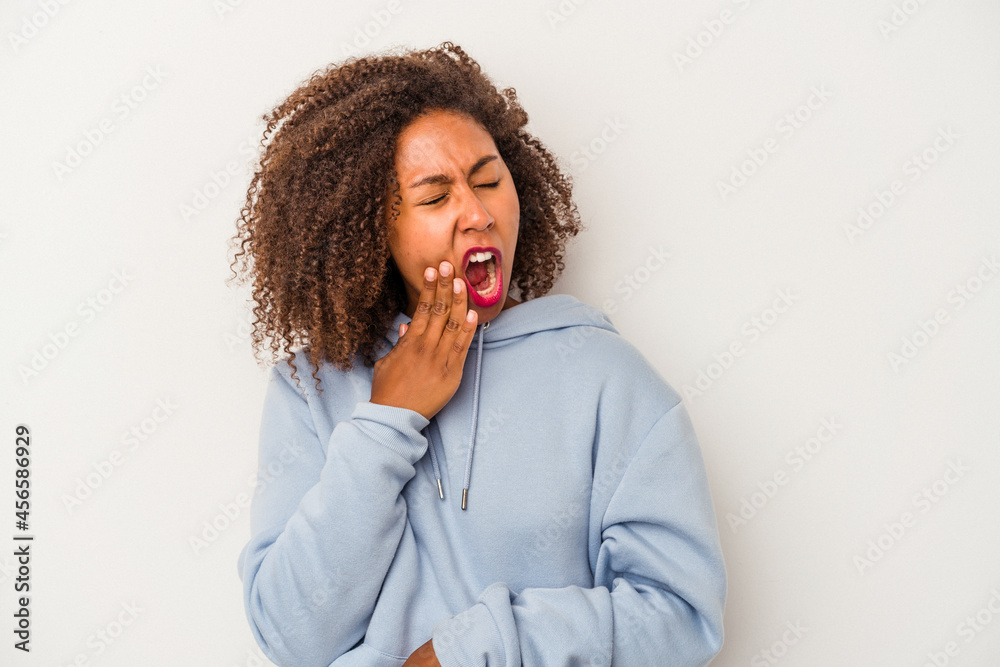 Young african american woman with curly hair isolated on white background yawning showing a tired gesture covering mouth with hand. Young african american woman with curly hair isolated on white background yawning showing a tired gesture covering mouth with hand.