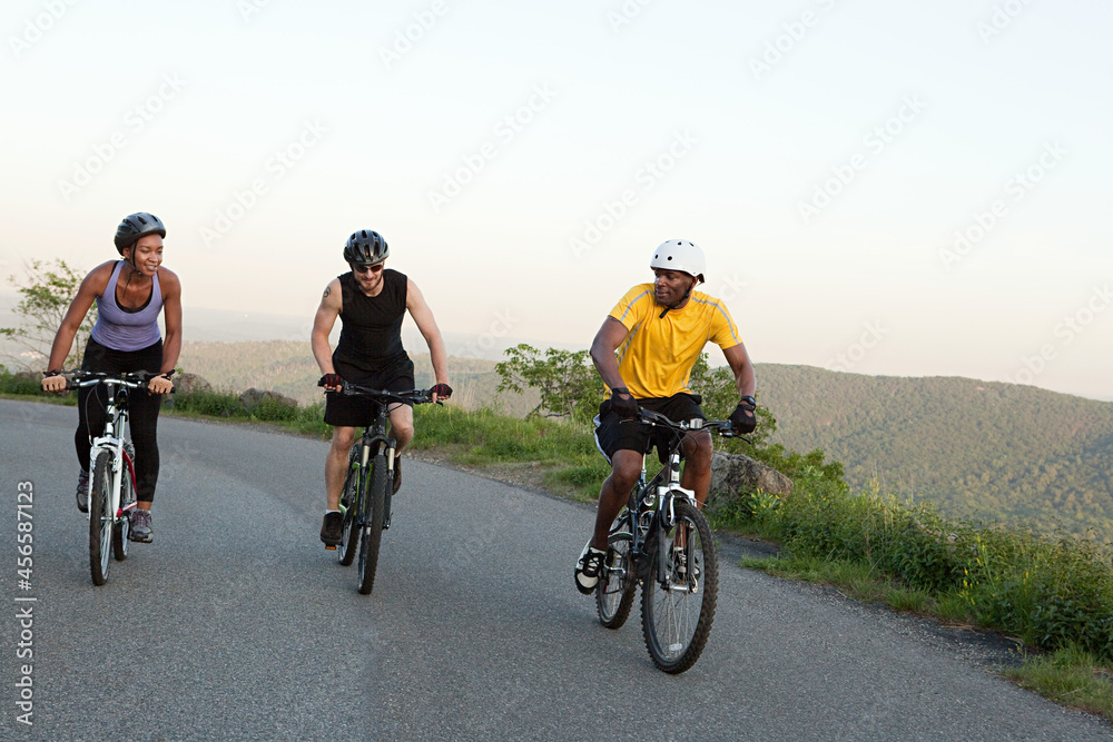 Naklejka premium Three cyclists on the road