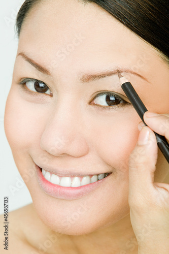 Young woman applying eyebrow pencil