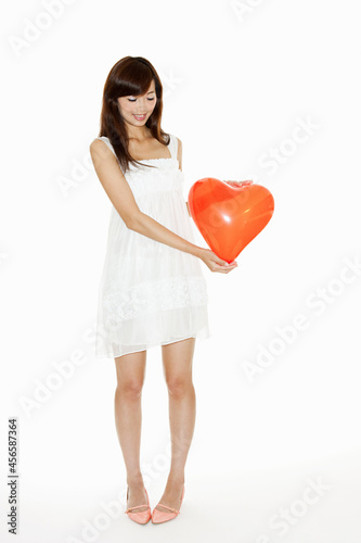 Woman holding red heart shaped balloon, studio shot © Cultura Allies