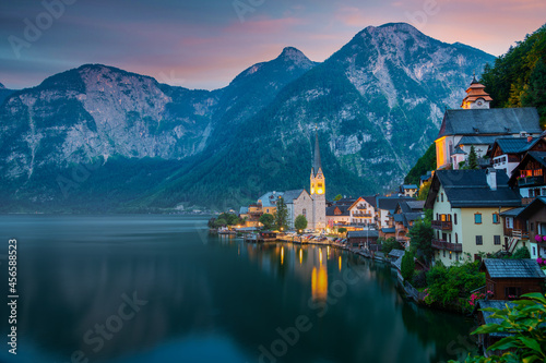 Hallstatt, Austria ; September 12, 2021 - A scenic picture postcard view of the famous village of Hallstatt reflecting in Hallstattersee lake in the Austrian Alps at dusk. 