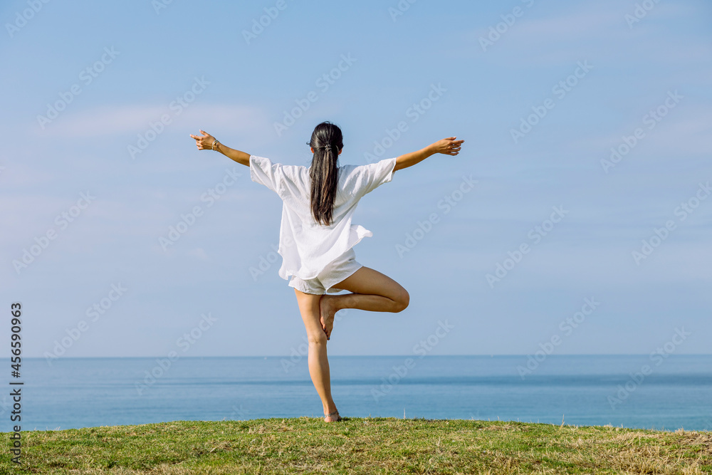 Unrecognizable woman standing in Tree pose on sea coast Unrecognizable woman standing in Tree pose on sea coast