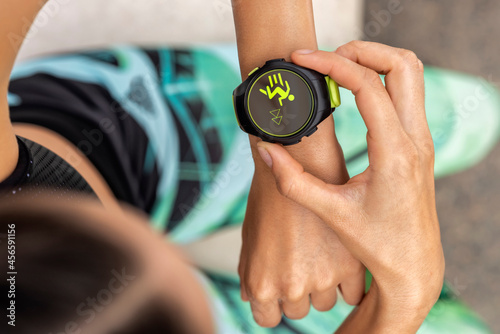Crop sportswoman checking fitness tracker