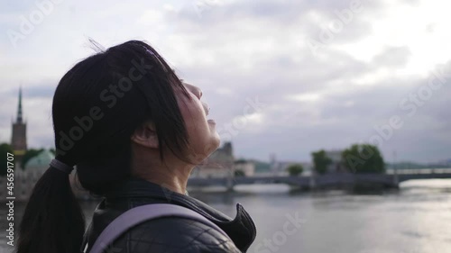 Close up Asian woman standing and seeing beautiful view of river in Sweden, taking a deep breath and getting some fresh air, traveling abroad on holiday, river background