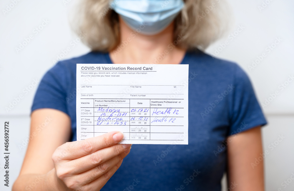 Vaccinated young woman showing COVID-19 Vaccination Record Card - obrazy, fototapety, plakaty 