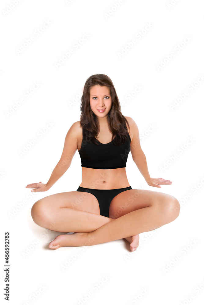 Smiling young woman wearing a black bikini in front of white studio background 