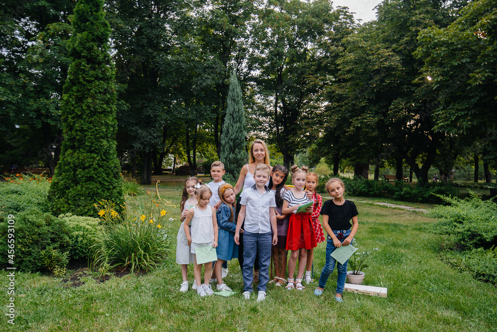 Obraz premium A teacher teaches a class of children in an outdoor Park. Back to school, learning during the pandemic