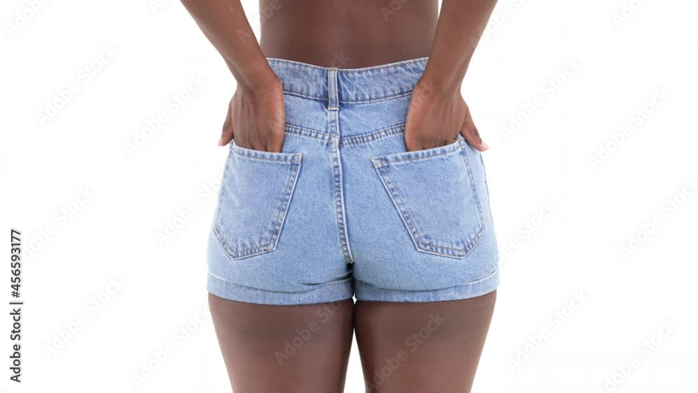 Close up of an african woman, slipping her hands into the back pocket of her jeans, and swaying from side to side. Isolated on a white background.