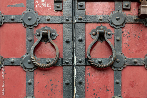 Obraz na plátně Red ancient gates with the metal fittings and the round doorknobs