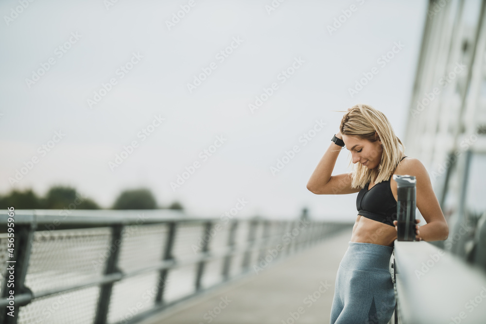 Woman Holding Water Bottle And Looking Her Abdominal Muscles After Outdoor Working Out