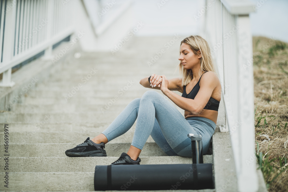 Woman Looking On Smartwatch While Sitting On The Stairs Before Outdoor Working Out