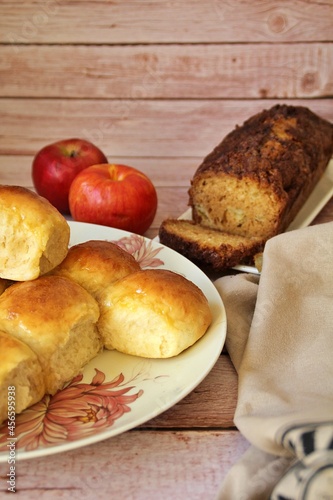 homemade yeast buns, brioche buns, glowing buns, homemade baked goods on a plate, cinnamon cake with apples, fresh apple fruit, red apples