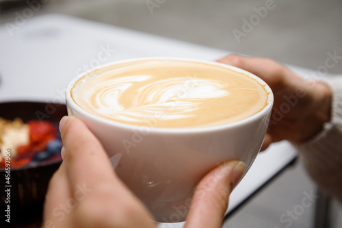 Young hands holding a coffee outdoors. Healthy breakfast