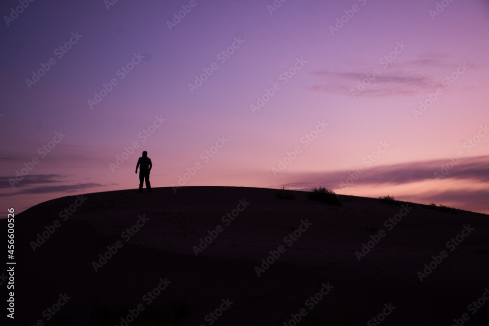 Silhouette of a man standing on a dune at sunrise